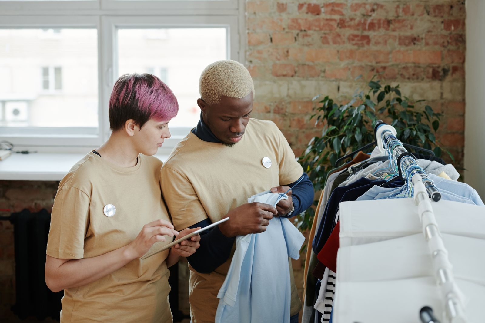 Two adults sort clothes on a rack indoors, showcasing teamwork and community service