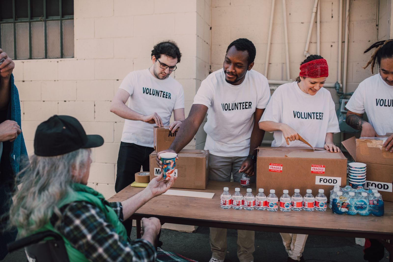 Volunteers distribute food and drinks to the needy at an outdoor charity event